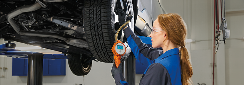 A Subaru technician checking tire pressure. | Subaru of Naples in Naples FL