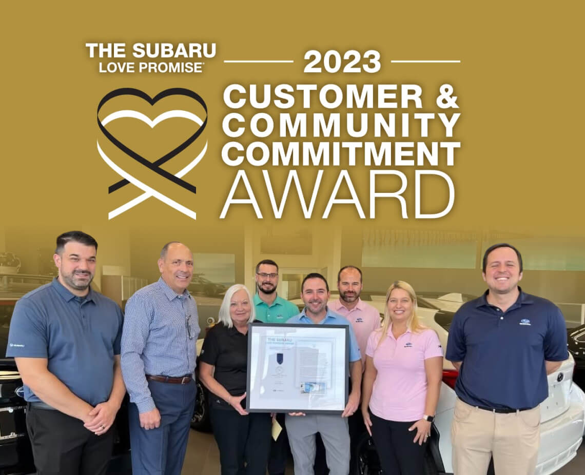 Subaru of Naples shown accepting an award over the 2023 Subaru Customer & Community Commitment Award logo.