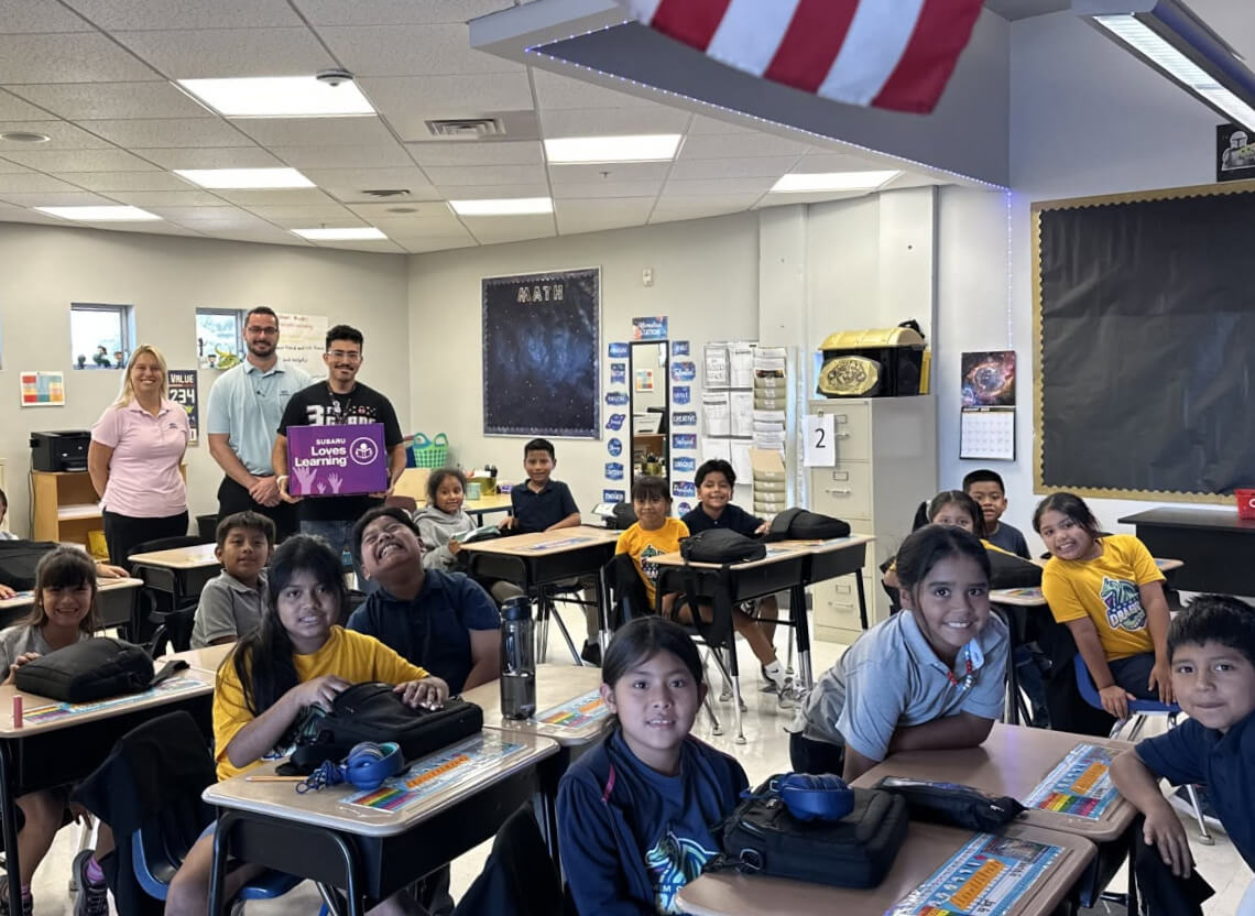 A classroom of excited children with Subaru of Naples team members smiling in the back.