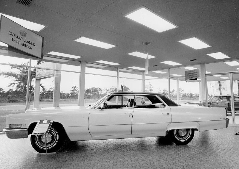 A classic white Cadillac sedan is displayed in a showroom