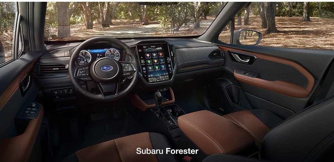 Subaru Forester interior featuring the steering wheel, digital instrument cluster, center touchscreen, and brown and black seating.
