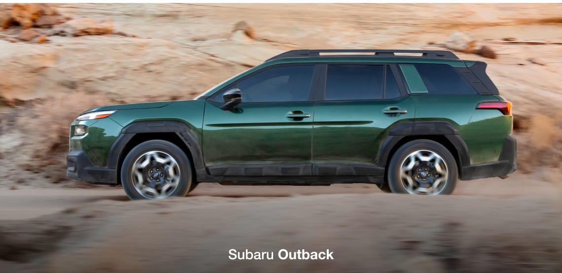 Green Subaru Outback driving off-road through a rocky desert landscape, shown in side profile.