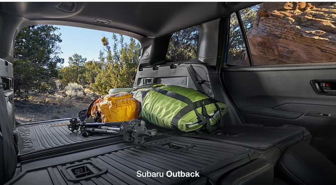 Subaru Outback cargo area loaded with camping gear and trekking poles with the rear seats folded down.